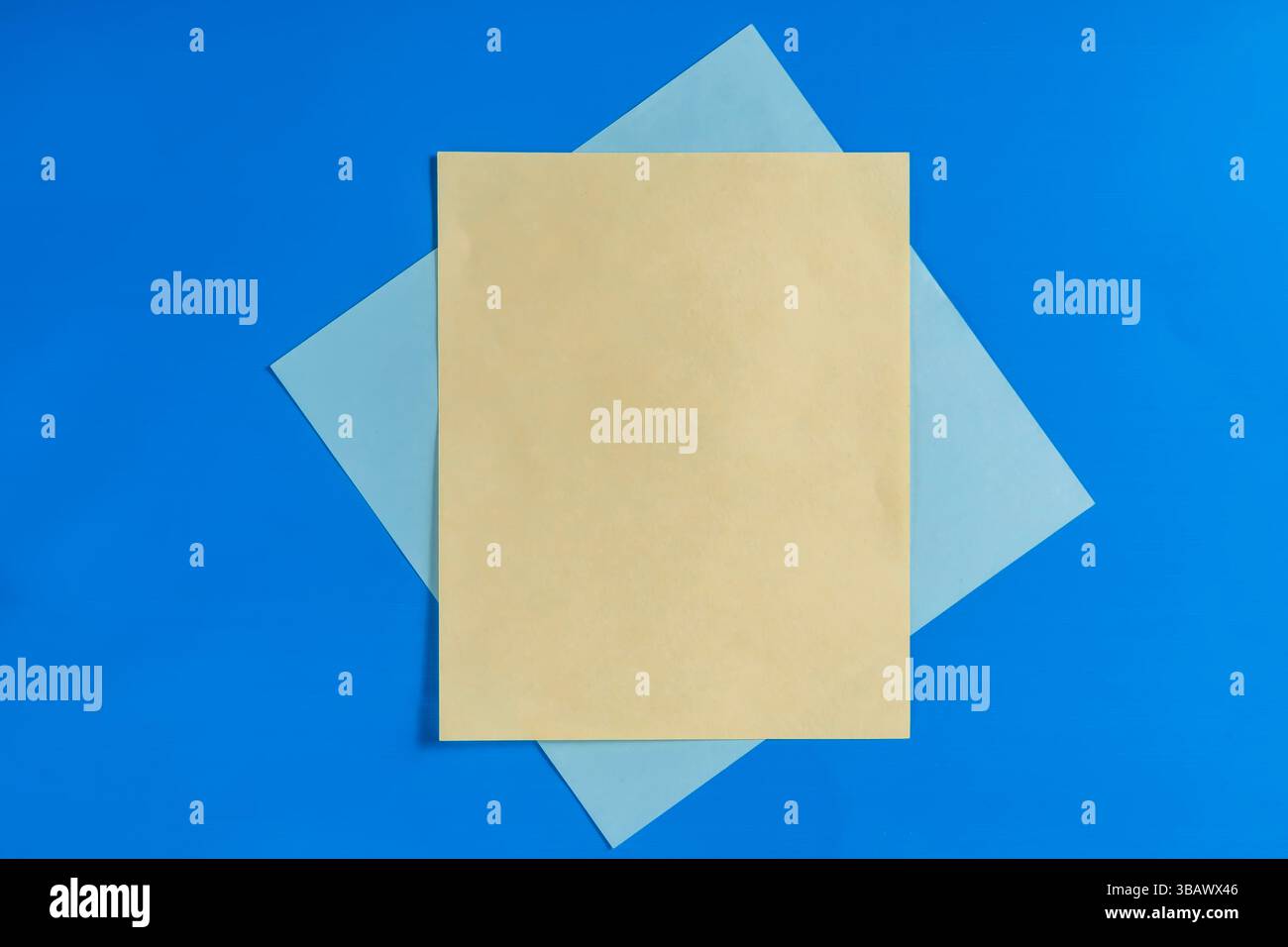 I fogli gialli e blu sono disposti in modo creativo su uno sfondo blu brillante, creando una composizione semplice ma accattivante adatta per il design o il design Foto Stock