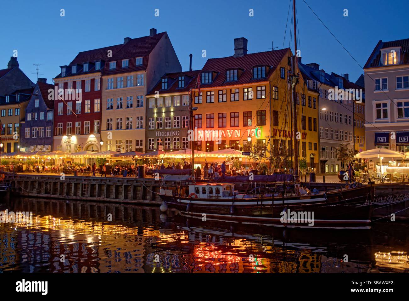 02.09.2024, Danimarca, Hovedstaden, Copenhagen - atmosfera serale sul canale Nyhavn nel quartiere di Frederiksstaden. La gente si siede fuori sotto il Foto Stock
