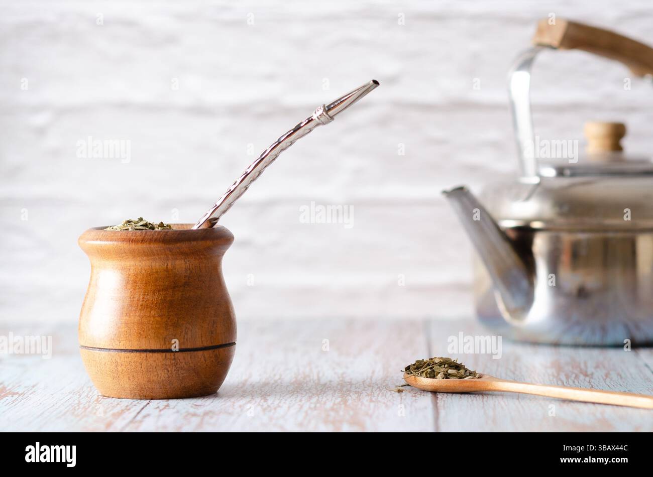 Un compagno di legno con bombilla, un cucchiaio con Yerba mate e un bollitore, su sfondo bianco. Foto Stock