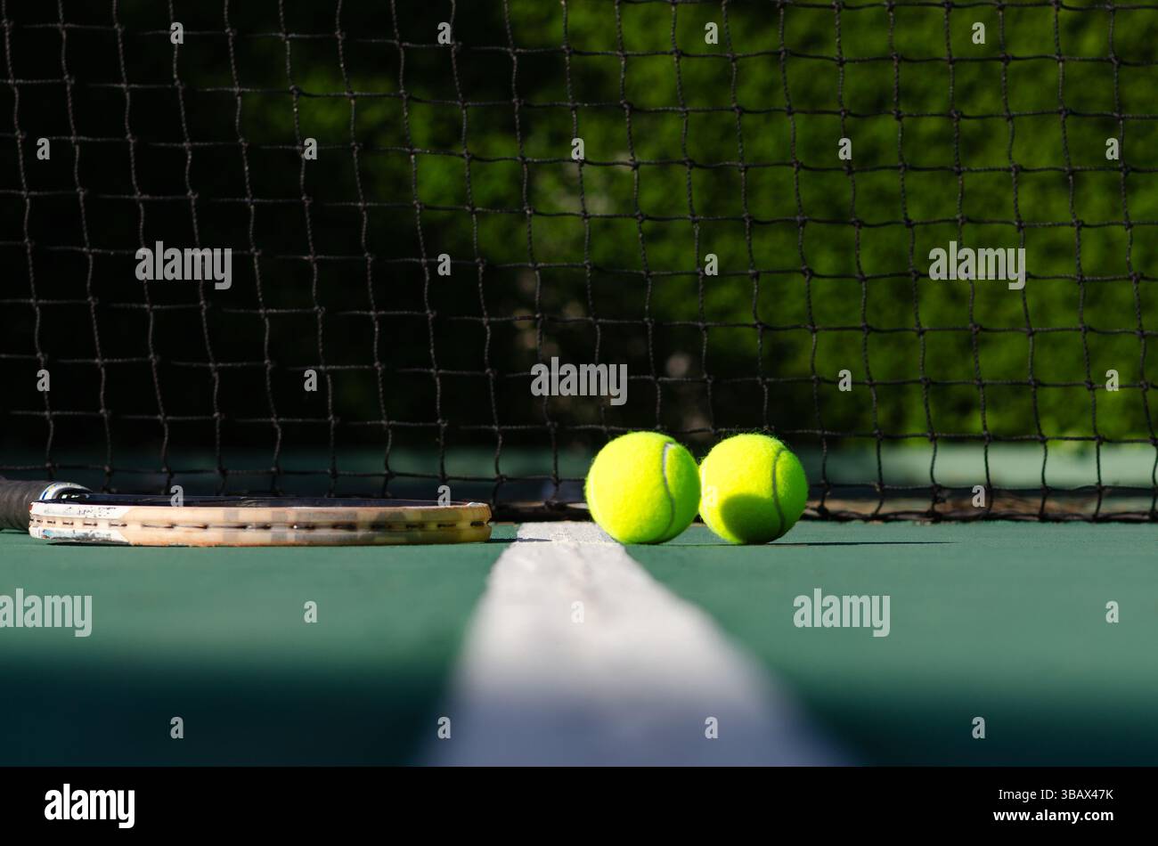 Una racchetta e due palle da tennis in un campo da tennis. Foto Stock