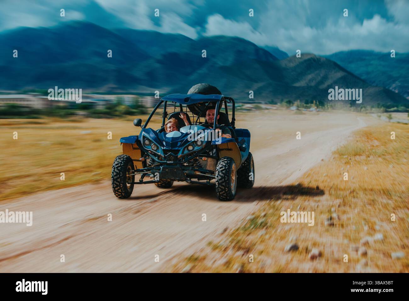 Padre e figlio guidano un buggy veloce su una strada di montagna, movimento sfocato Foto Stock