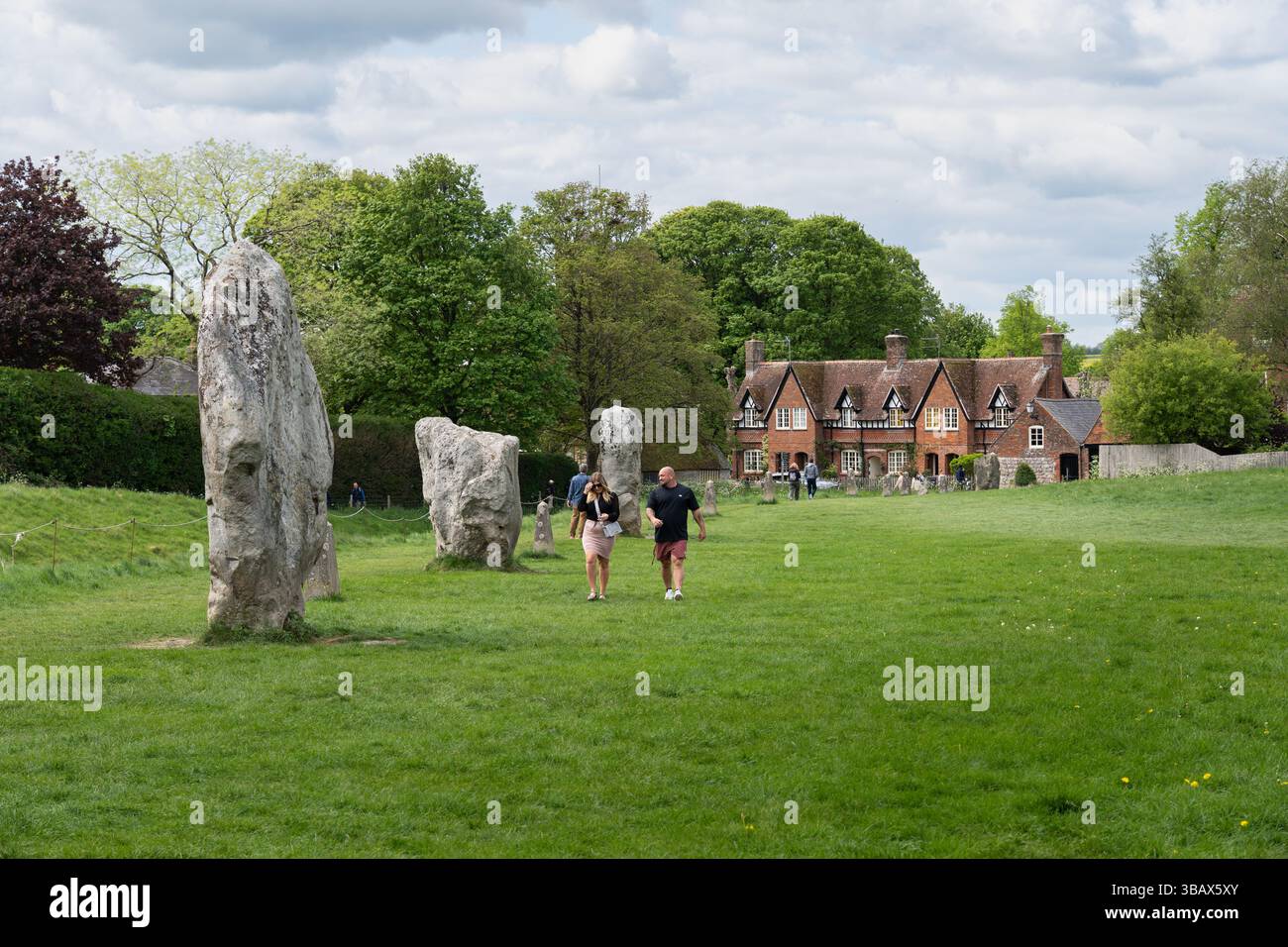 I visitatori del famoso cerchio di Avebury Henge & Stone, sito Patrimonio dell'Umanità, nel settore sud-occidentale, passeranno davanti alle pietre erette, Wiltshire, Regno Unito Foto Stock