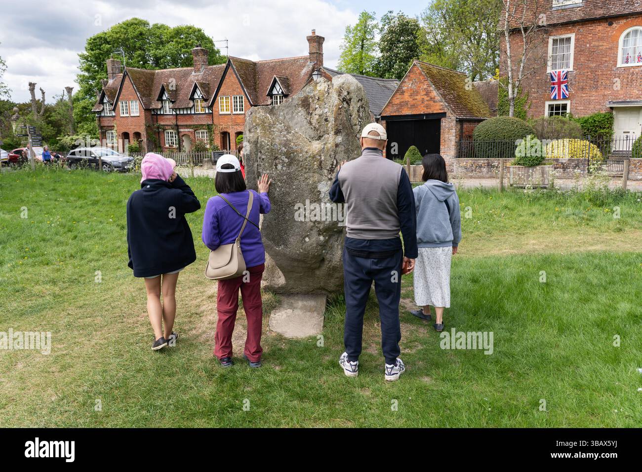 Il gruppo del tour si è riunito intorno e ha toccato la pietra del fabbro presso l'Avebury Henge & Stone Circle, sito patrimonio dell'umanità, Wiltshire, Regno Unito Foto Stock