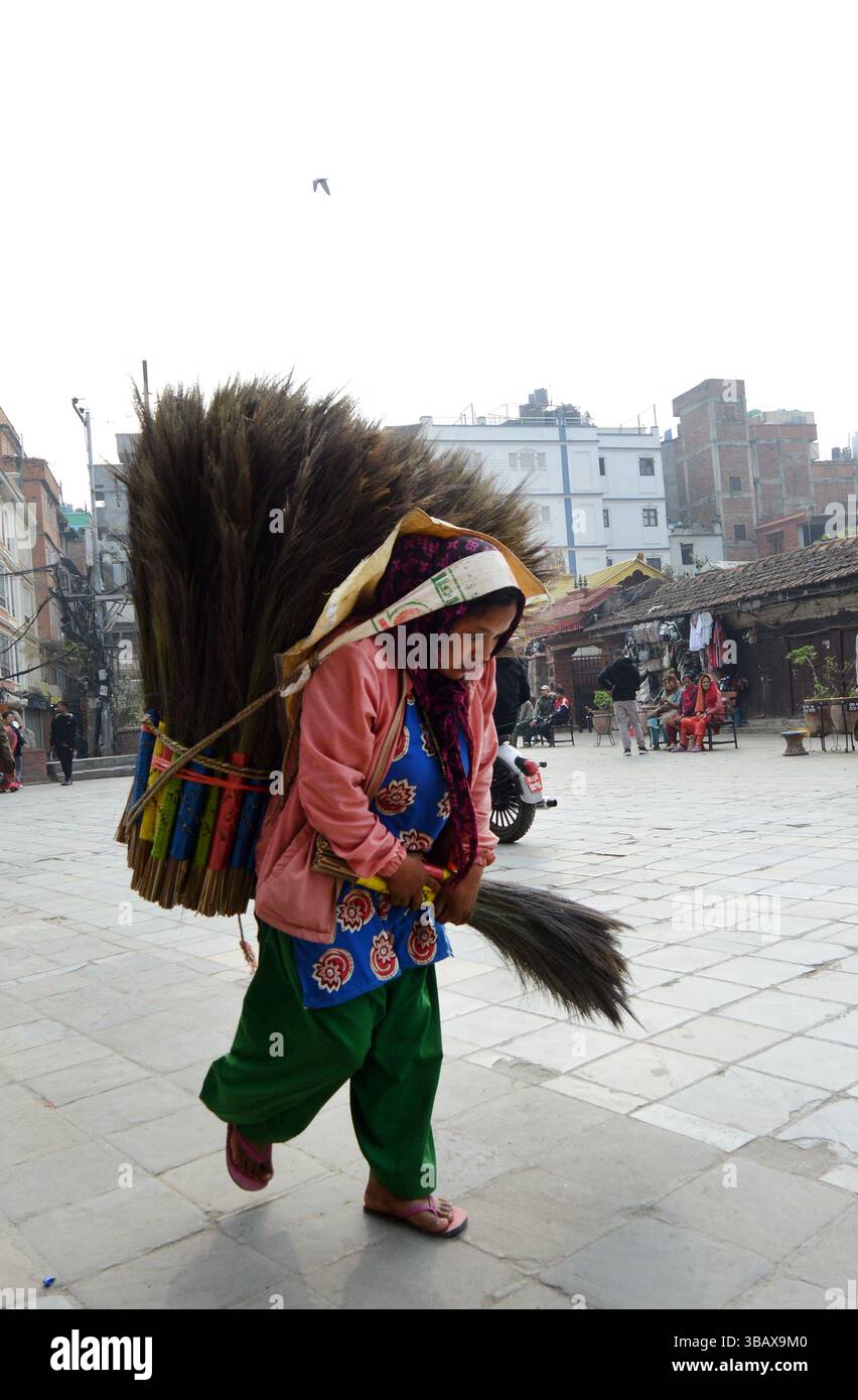 Una donna nepalese che vende spazzatrici tradizionali in paglia (Kucho) a Kathmandu, Nepal. Foto Stock