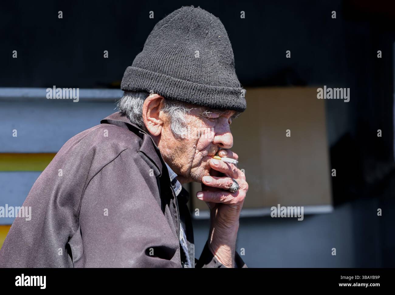 Un vecchio villaggio russo ha perso il pensiero, fumando una sigaretta in solitudine, riflettendo sulla vita con uno sguardo malinconico e lontano Foto Stock
