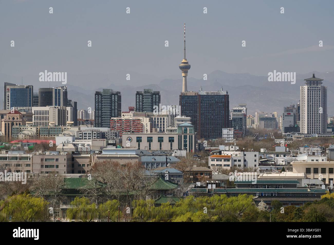 Skyline nel centro di Pechino con la torre CCTV e gli edifici per uffici sotto il cielo limpido, adagiati contro montagne lontane Foto Stock