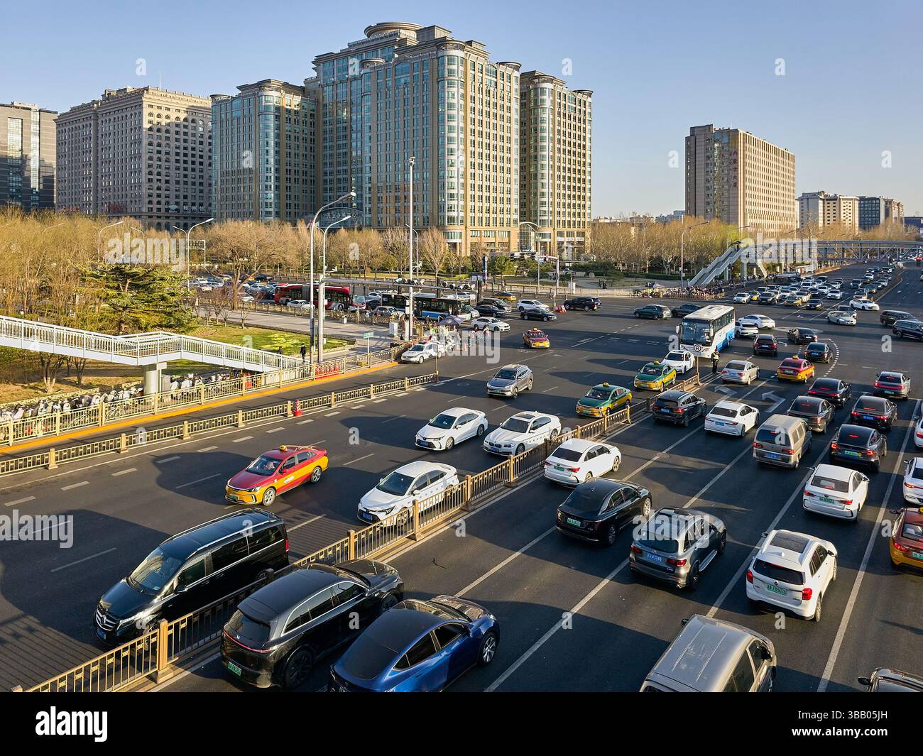 Intersezione stradale a più corsie a Pechino con traffico intenso durante il giorno e moderni grattacieli sullo sfondo. Foto Stock