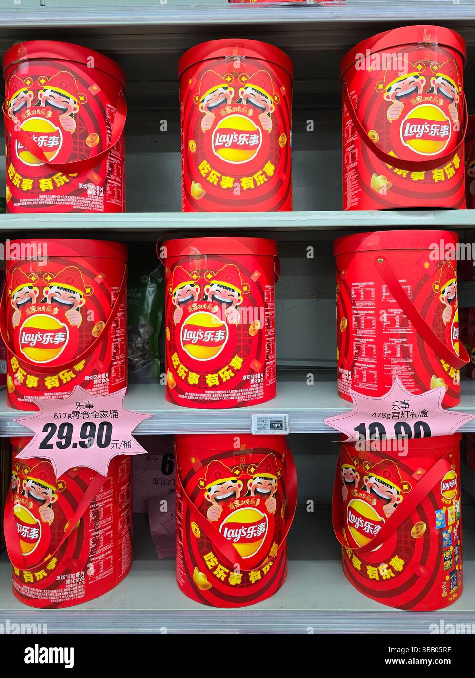 Scatole regalo colorate per il capodanno cinese di Lay disposte sugli scaffali dei supermercati, decorate con mascotte da ballo dei leoni e cartellini a prezzi convenienti. Foto Stock