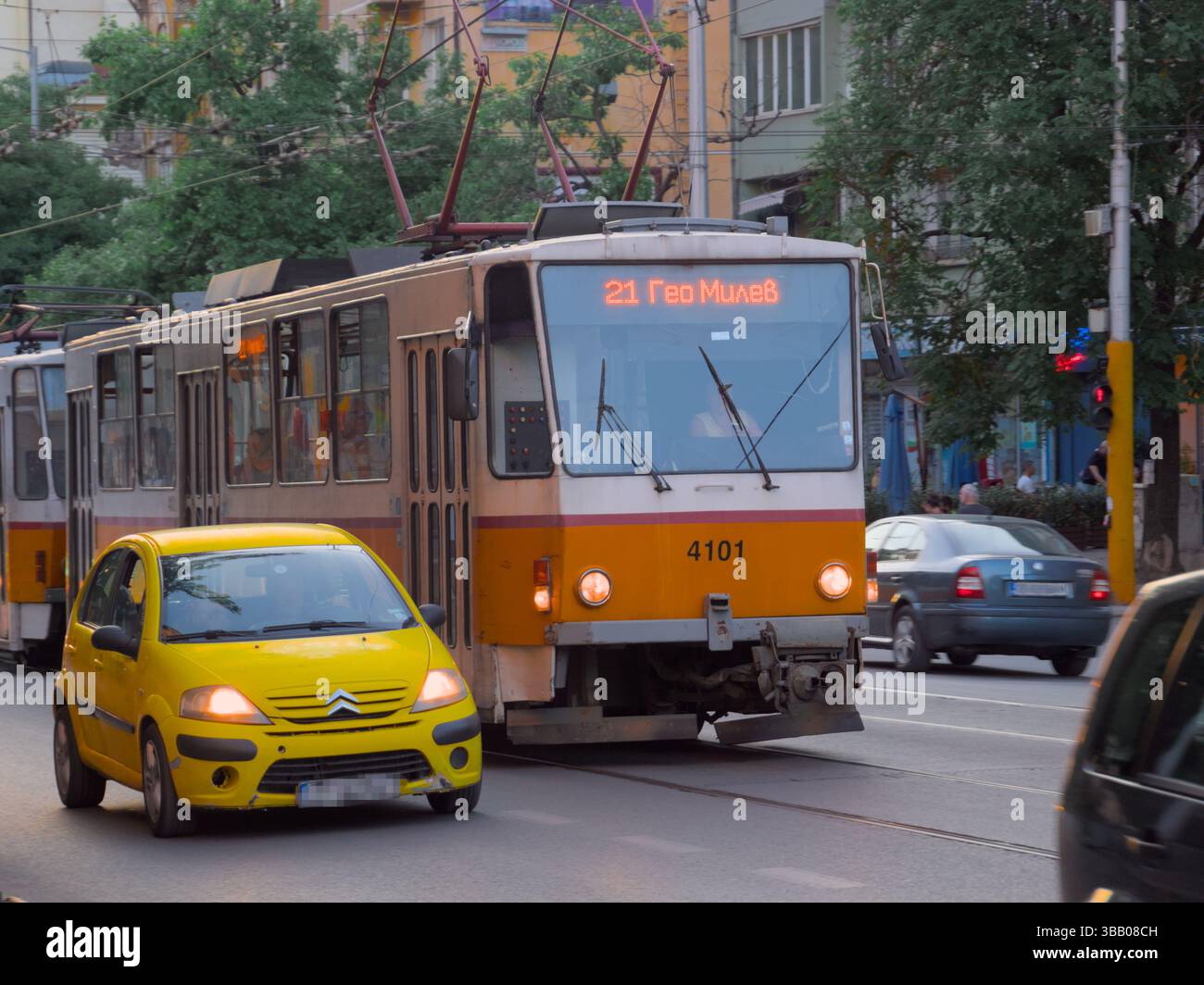 Tram urbano e auto gialla su una trafficata strada cittadina a Dusk, Sofia Foto Stock