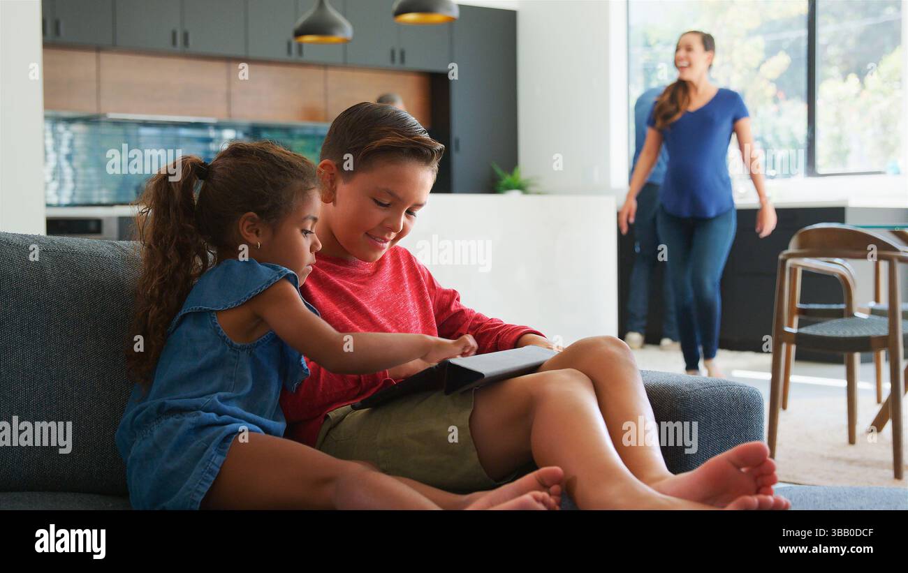 Bambini che giocano ai videogiochi su un tablet digitale durante la riunione di famiglia A casa Foto Stock