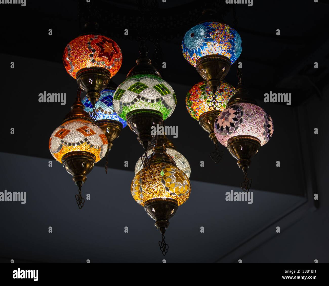 Un gruppo di tradizionali lanterne a mosaico turche appese al soffitto, ognuna caratterizzata da particolari motivi di vetro artigianali in colori vivaci. L'oscurità Foto Stock