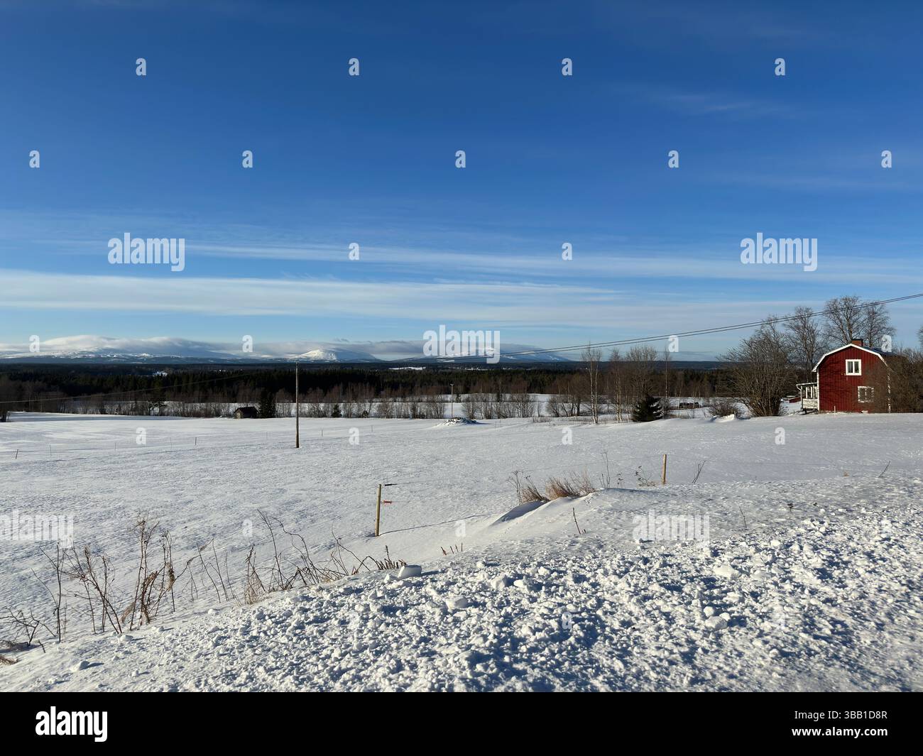 Un tranquillo paesaggio invernale con una casa rossa annidata nella neve Foto Stock