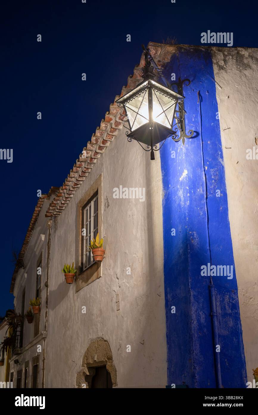 Portogallo, regione di Oeste, Óbidos, Lanterna a staffa sull'architettura tradizionale su Rua Direita all'interno della storica Cittadella murata di notte Foto Stock