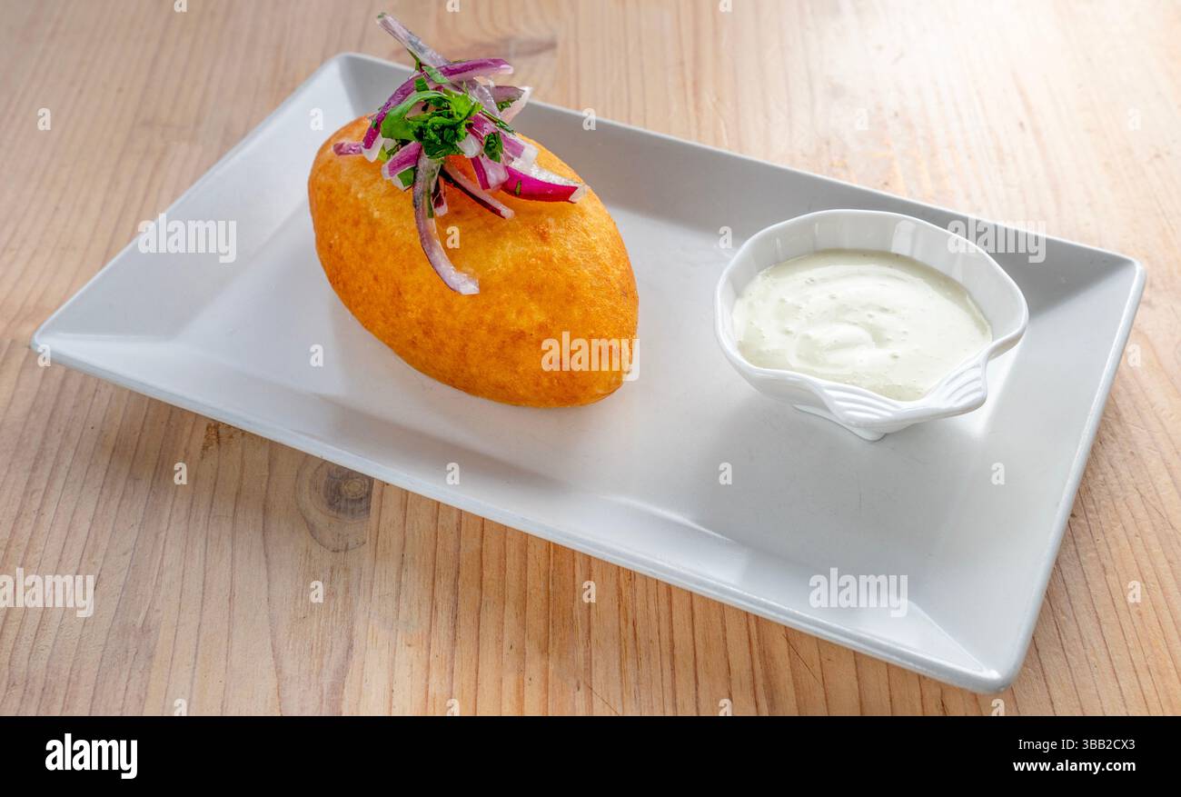 Anticuchos, un piatto tradizionale peruviano con spiedini di carne alla griglia, patate, mais e salsa gialla al peperoncino aji Foto Stock