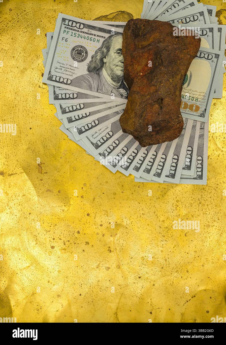 Le banconote da un dollaro sono sparse in un fan su uno sfondo dorato. La pietra ocra rossa giace sulle banconote. Visione metaforica di fare soldi e diventare ricchi. Foto Stock