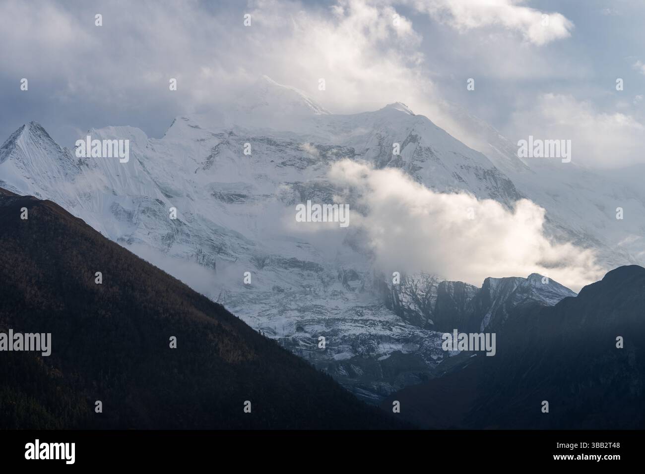 L'Annapurna II sorge dietro le nuvole all'alba, vista dal villaggio di Upper Pisang sul circuito dell'Annapurna nell'Himalaya del Nepal Foto Stock