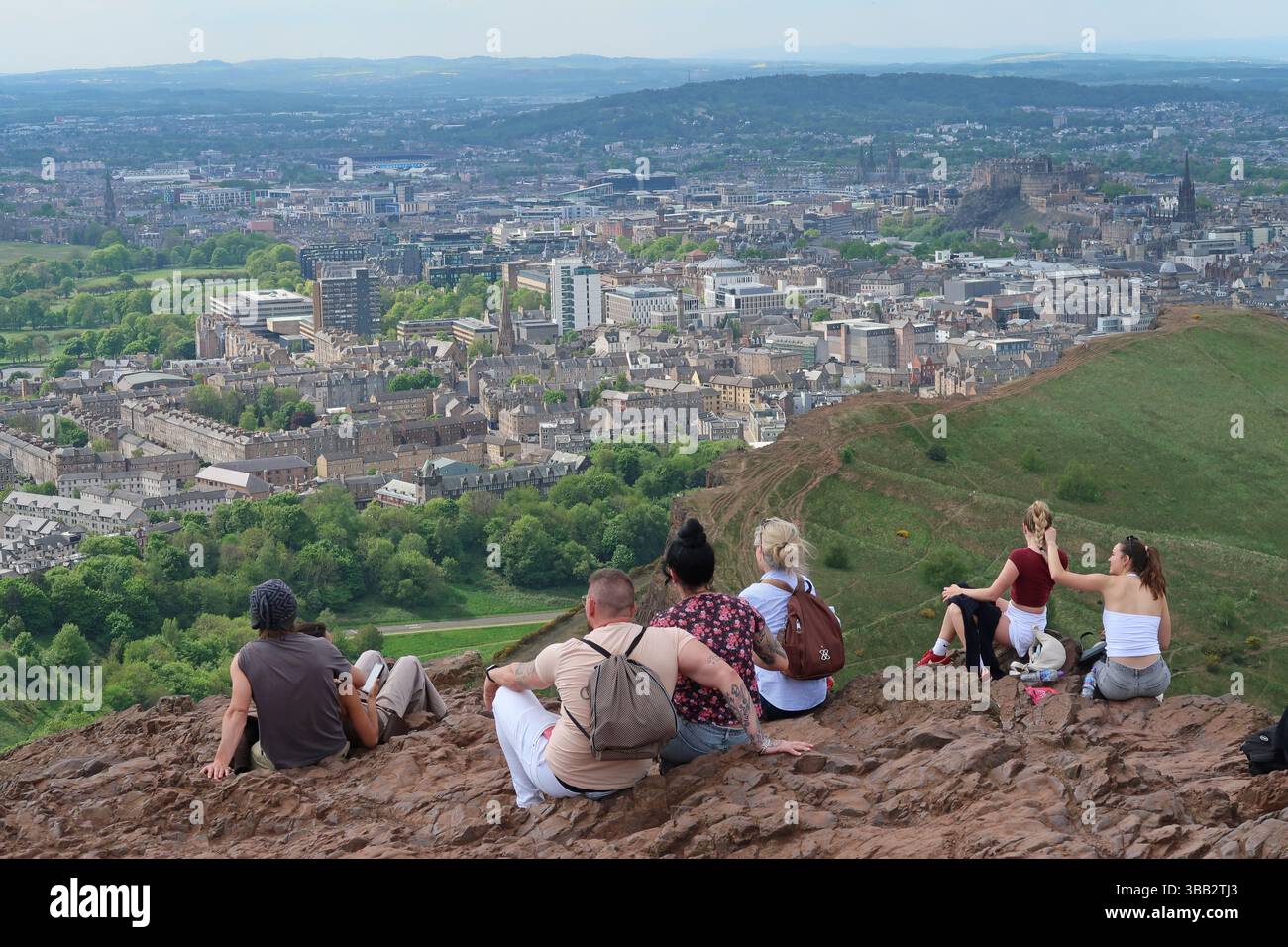 Arthur's Seat, Edimburgo, Scozia. I giovani ammirano la vista sulla città dal famoso monumento in un giorno di sole primaverili. Foto Stock
