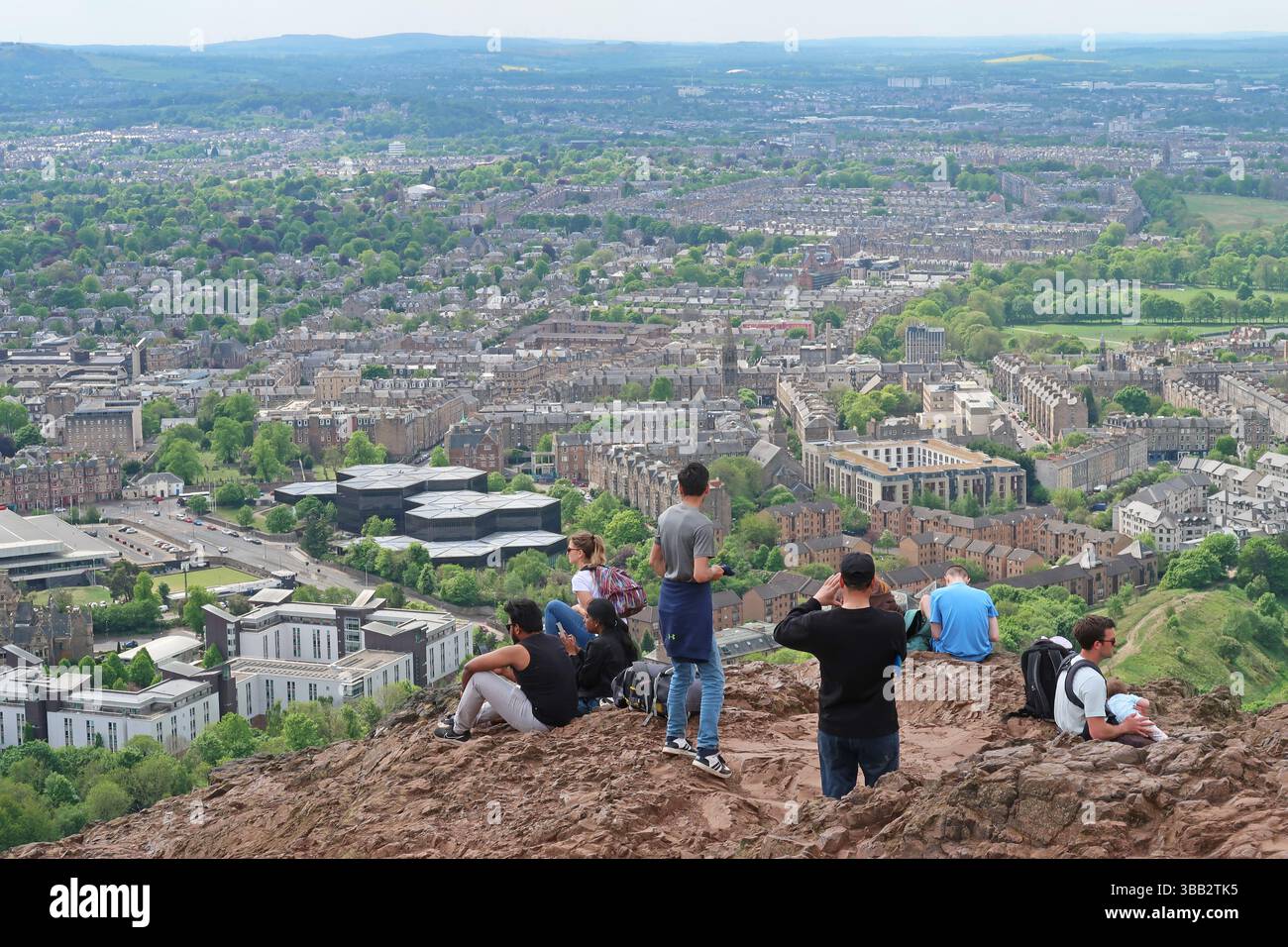 Arthur's Seat, Edimburgo, Scozia. I giovani ammirano la vista sulla città dal famoso monumento in un giorno di sole primaverili. Foto Stock