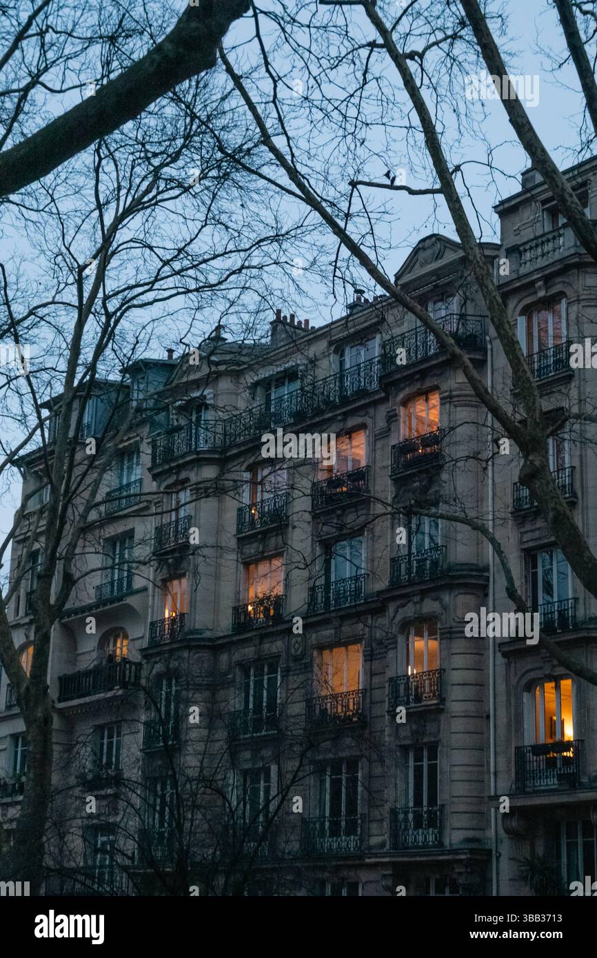 Classico edificio di appartamenti parigino al crepuscolo con finestre illuminate Parigi, Francia Foto Stock