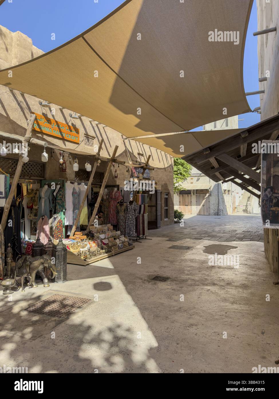 Un mercato soleggiato con bancarelle di abbigliamento ed edifici tradizionali sotto una grande tenda, il centro storico di Dubai a Dubai Greek, Dubai, Emirati Arabi Uniti, Asia Foto Stock