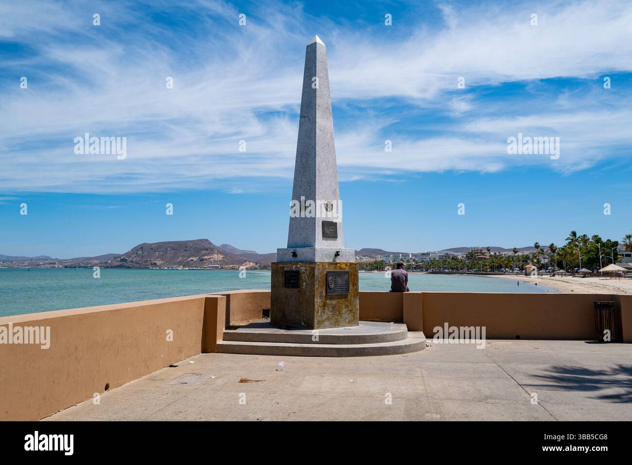 Un uomo siede accanto all'Obelisco a los Niños Héroes è un monumento situato lungo il Malecón a la Paz, BCS Messico. Foto Stock