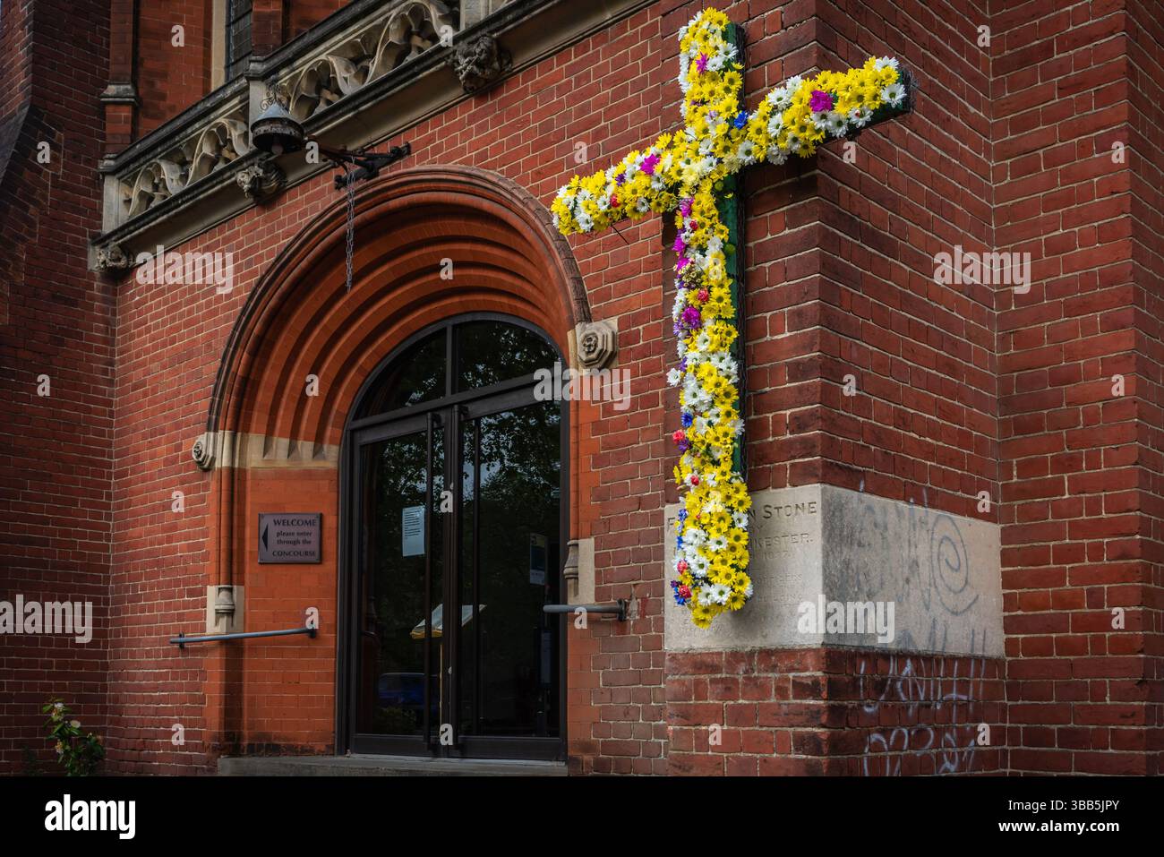 Croce cristiana decorata con fiori colorati per Pasqua all'esterno della chiesa di St Andrews lungo il viale di Southampton, Inghilterra, Regno Unito Foto Stock
