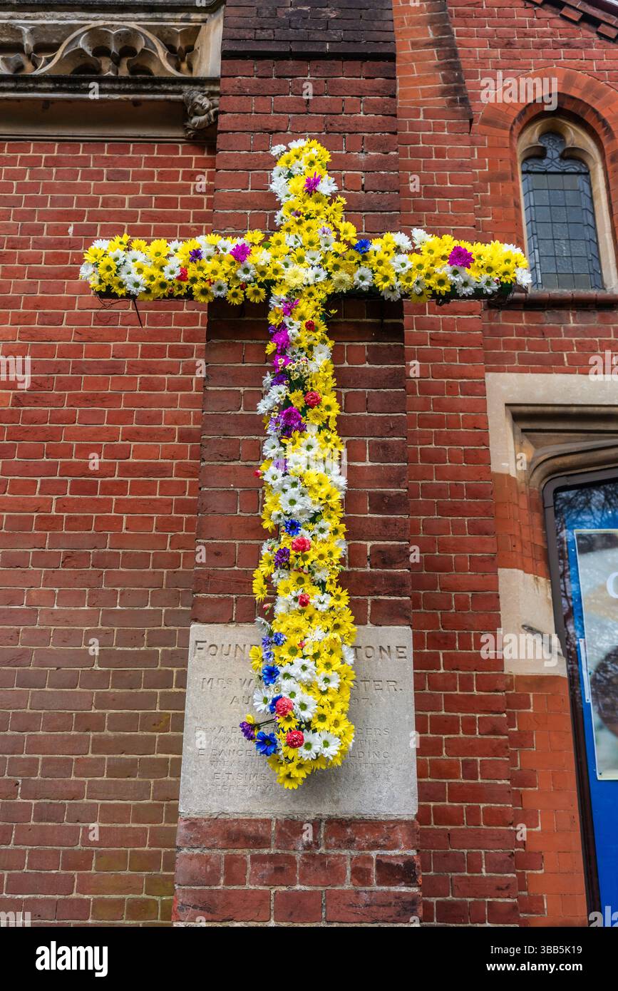 Croce cristiana decorata con fiori colorati per Pasqua all'esterno della chiesa di St Andrews lungo il viale di Southampton, Inghilterra, Regno Unito Foto Stock
