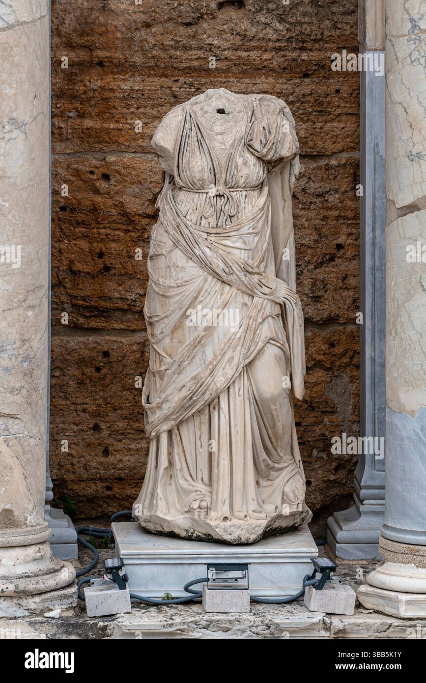 Una statua in marmo senza testa in drappeggi classici si erge in una nicchia di teatro a Hierapolis, incorniciata da un'antica architettura in pietra. Foto Stock