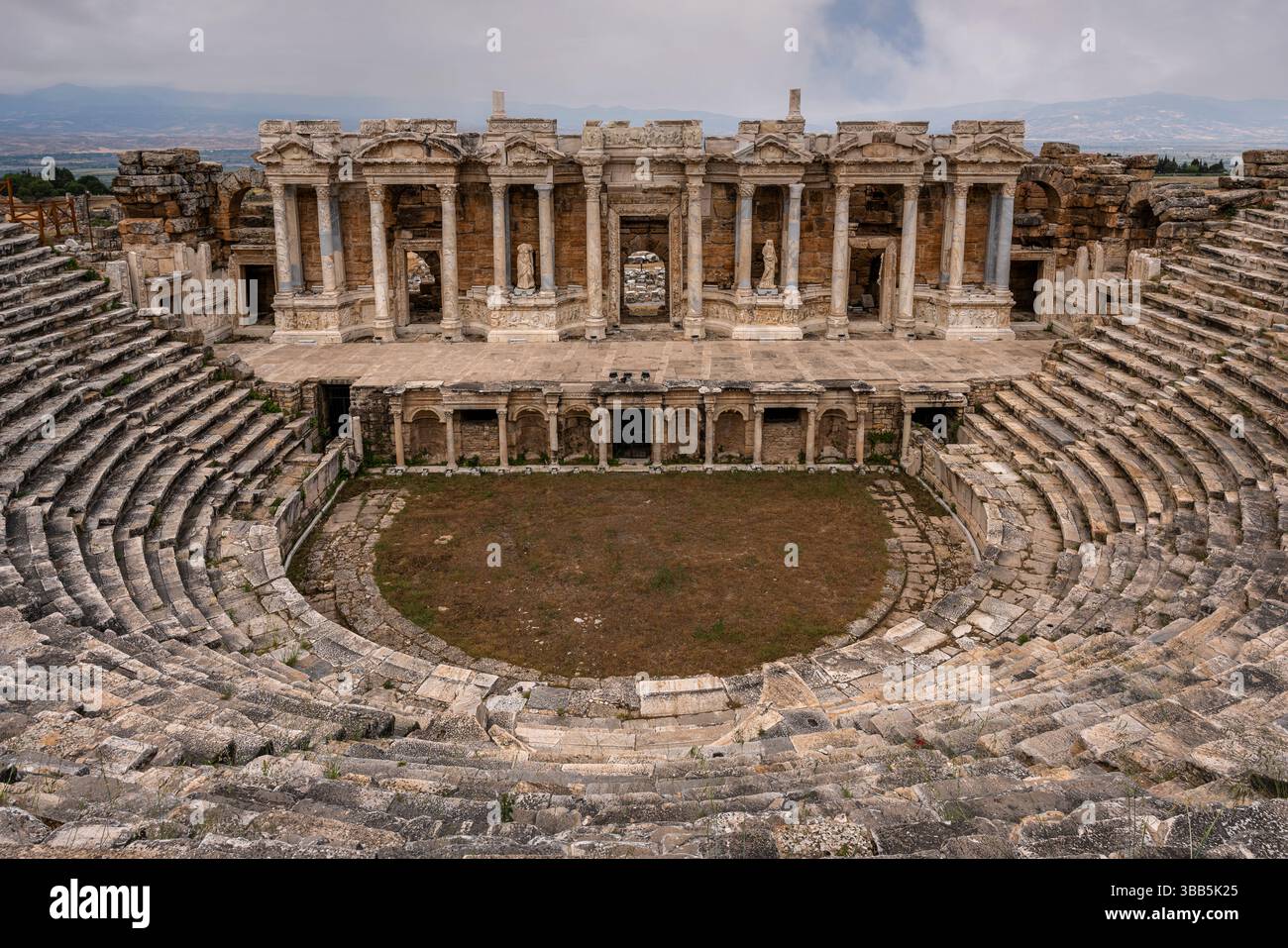 Il teatro romano di Hierapolis presenta un'ampia cavea semicircolare e un palcoscenico monumentale, ambientato contro l'altopiano di Pamukkale. Foto Stock