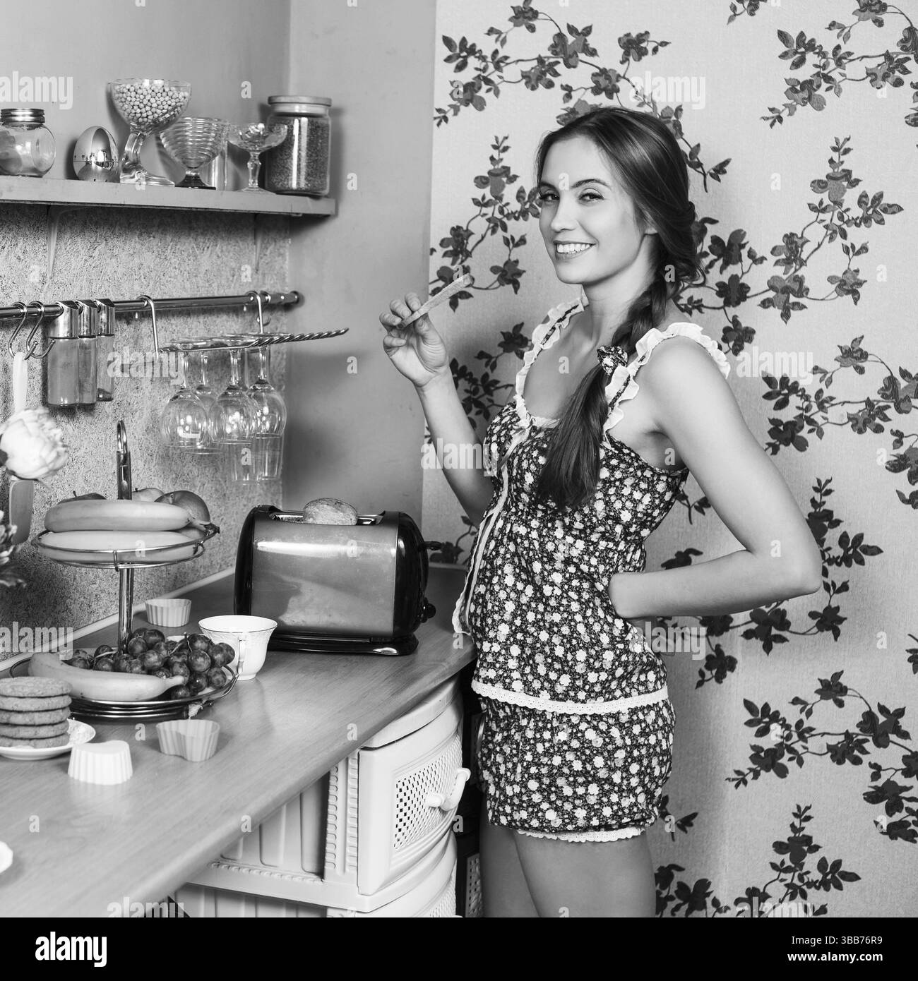 Bella casalinga che mangia toast nella sua cucina Foto Stock