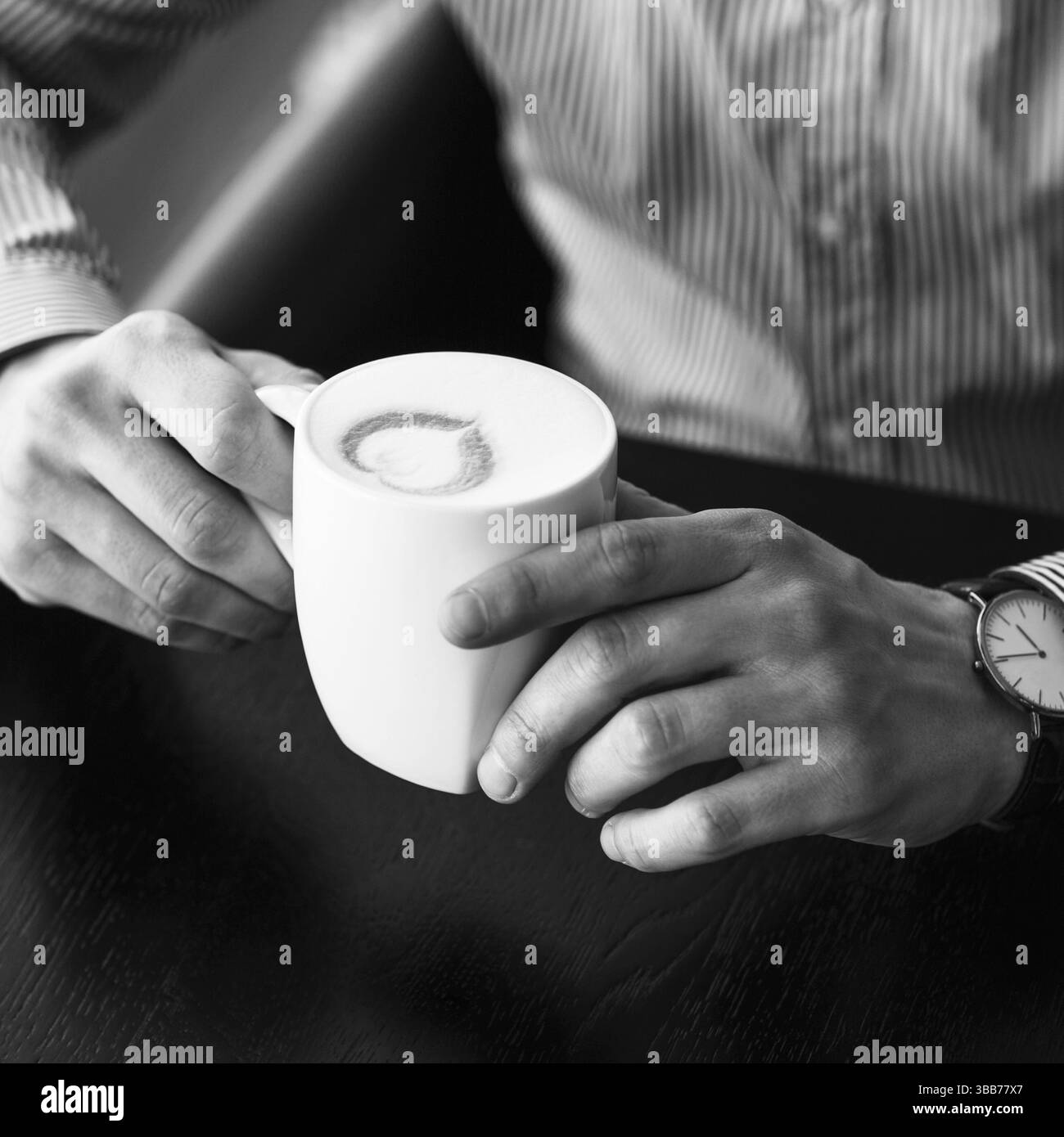 Imprenditore prendendo una pausa in ufficio come egli gode di una tazza calda di caffè aromatico, vista ravvicinata delle sue mani Foto Stock