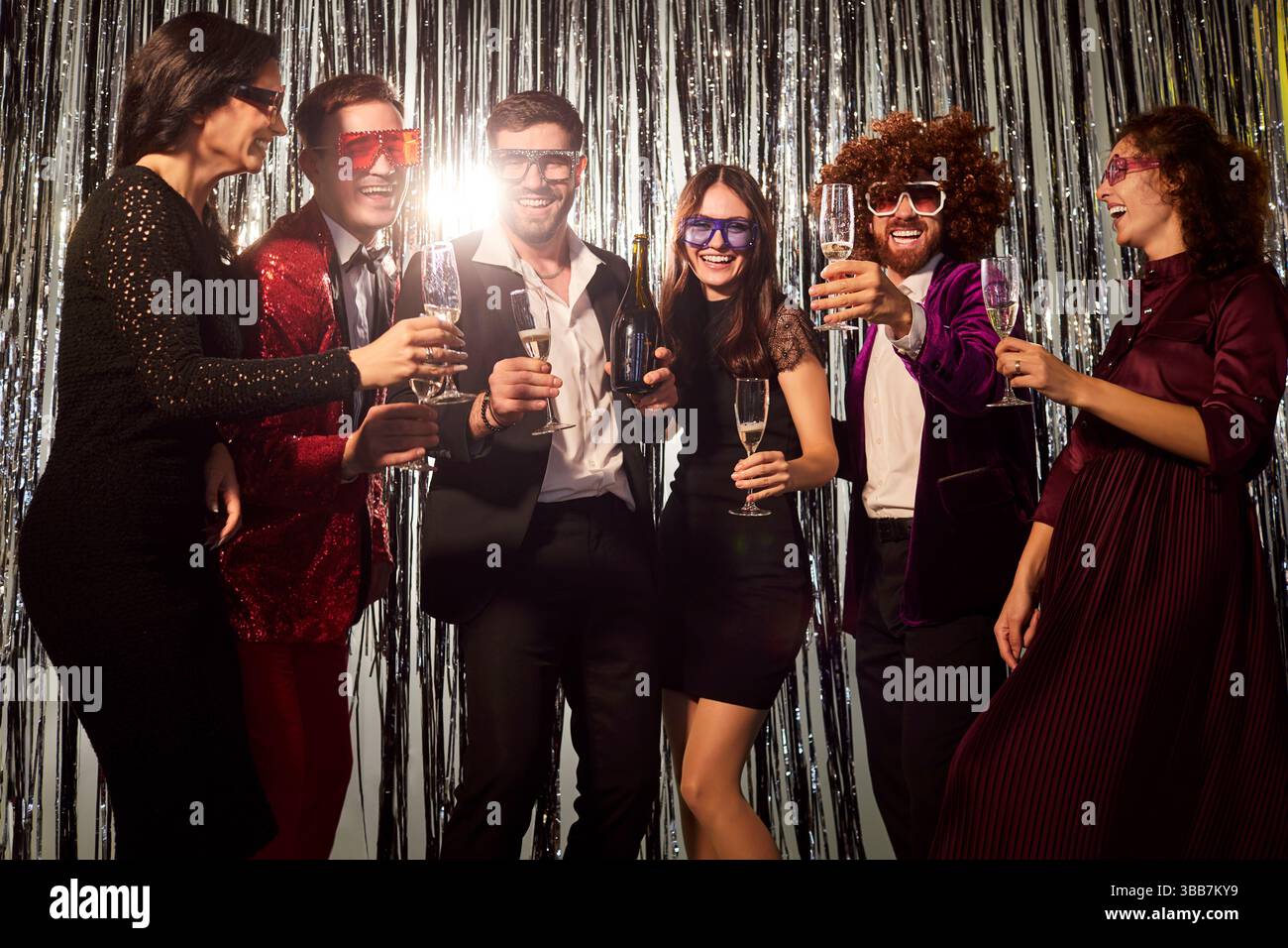 Allegri amici che ballano con bicchieri di champagne alla festa serale al nightclub Foto Stock