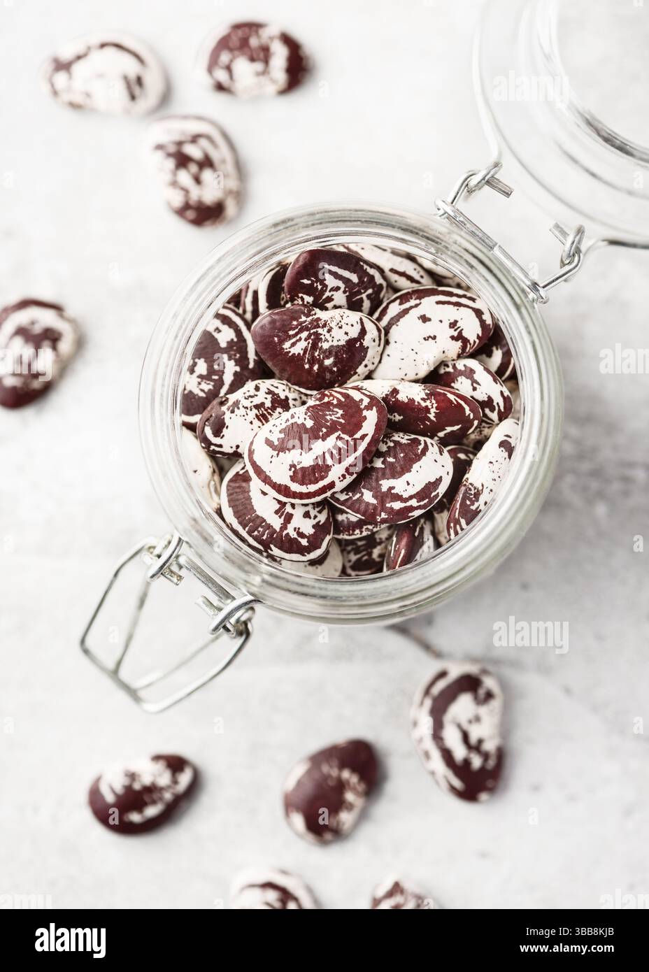 Bellissimi fagioli di lima di Natale (Phaseolus lunatus) di colore rosso e bianco crudi e secchi in un bicchiere. Cibo biologico o concetto di giardinaggio. Vie superiori Foto Stock
