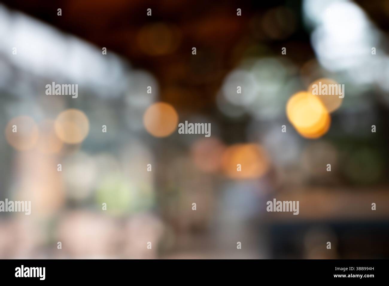 Un caffè sfocato con sfondo bokeh sfocato in ambienti interni con luce calda che crea un'atmosfera accogliente, un morbido effetto bokeh con luce circolare Foto Stock