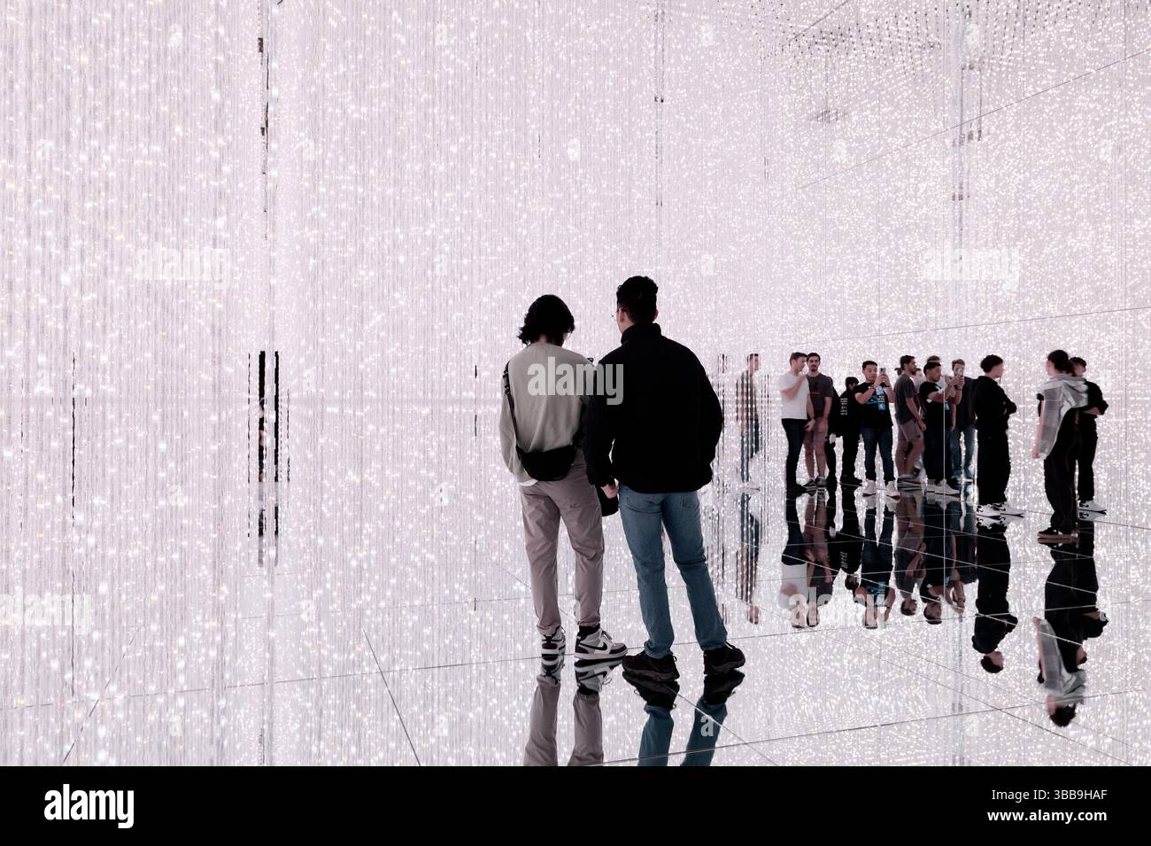 Le persone osservano un labirinto di luci al TeamLab Borderless Foto Stock