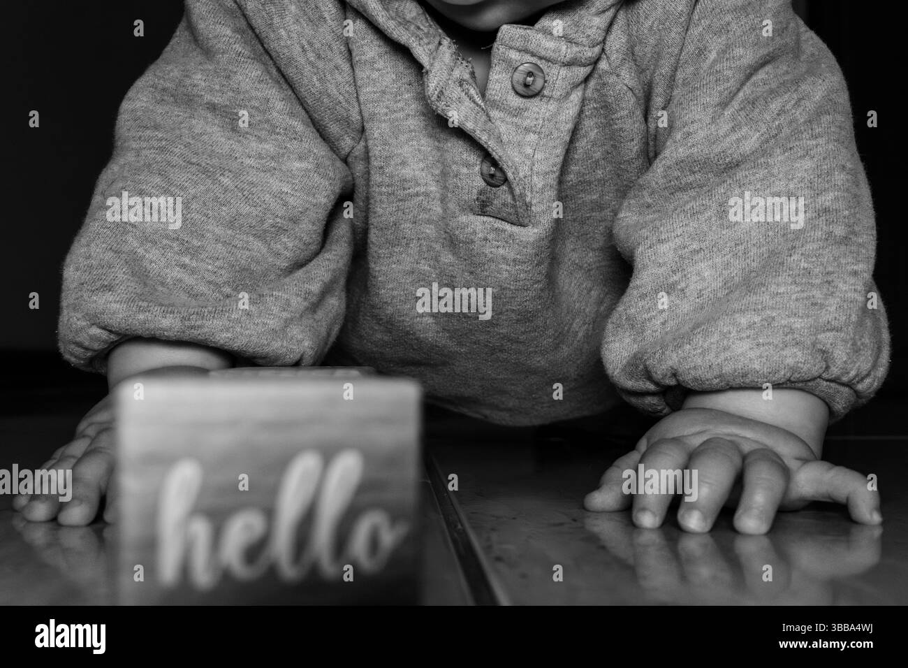 Foto in bianco e nero di un bambino che strizza con un cartello di benvenuto accanto a lui Foto Stock