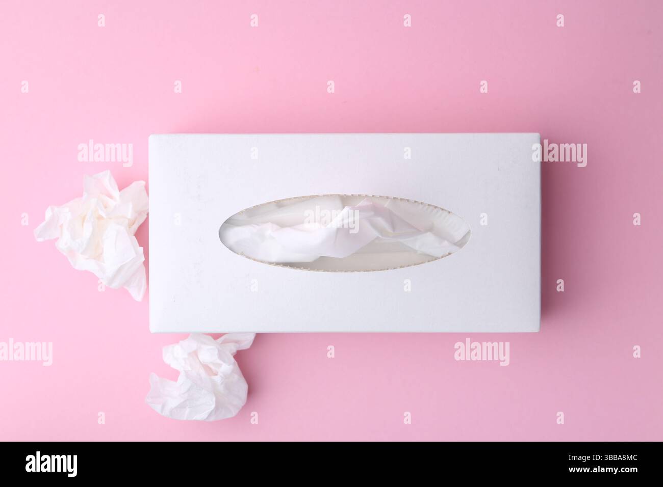 Scatola con fazzoletti di carta e fazzoletti su sfondo rosa, piatto Foto Stock
