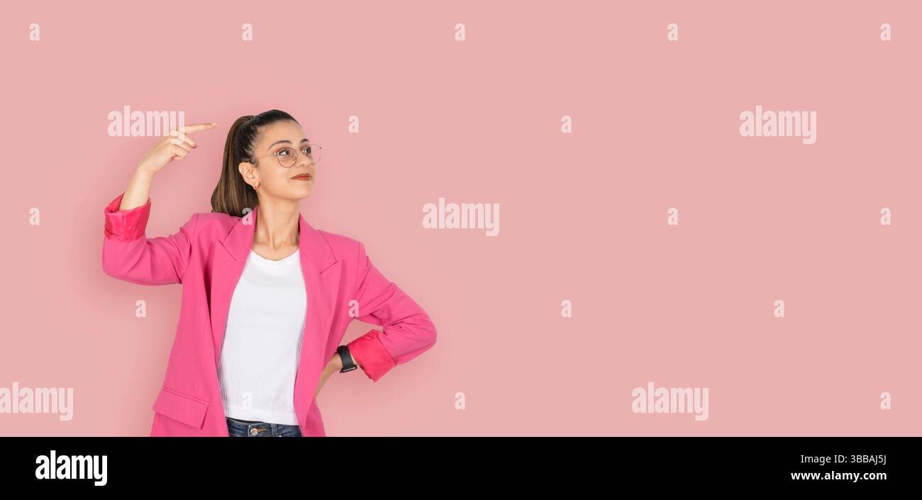 bruna donna d'affari caucasica che mostra spazio di copia. Area di lavoro dito puntato. Pubblicità, pubblicità, banner pubblicitari design sfondo rosa. Foto Stock