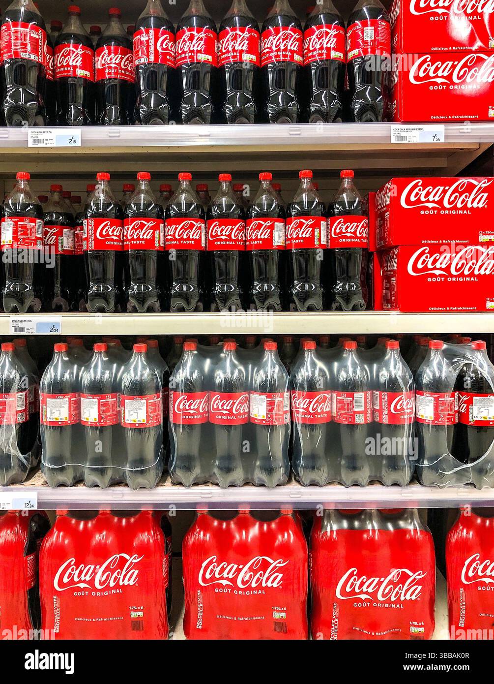 Scaffali del supermercato impilati con bottiglie e 6 confezioni di bibite Coca Cola - Francia. Foto Stock