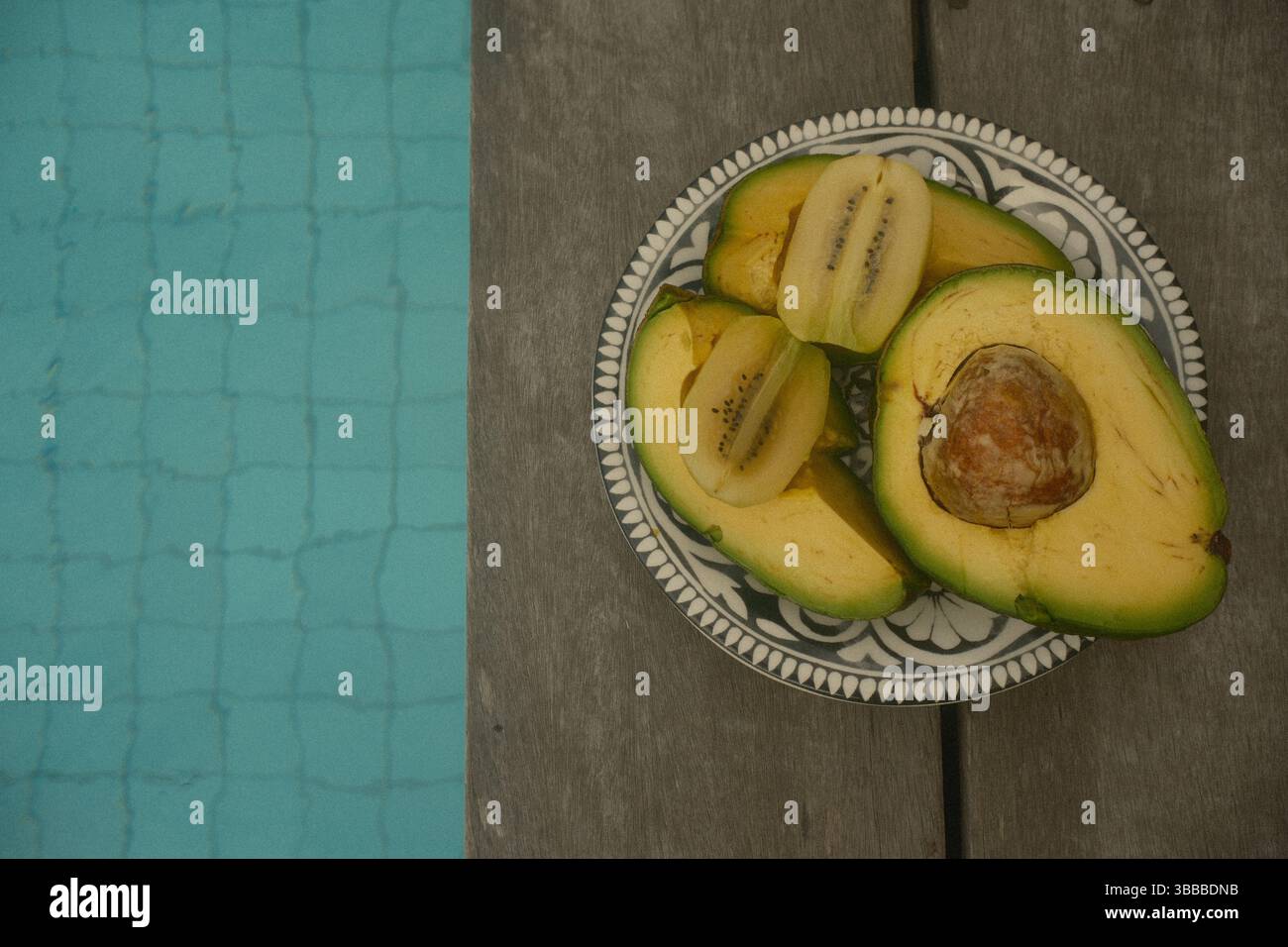 Un piatto di avocado affettato e kiwi dorati presso la piscina Foto Stock