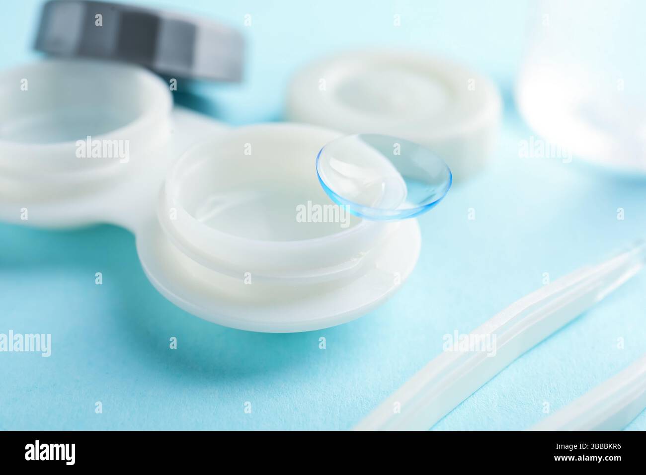 Lenti a contatto, custodia e pinzette su sfondo azzurro, primo piano Foto Stock