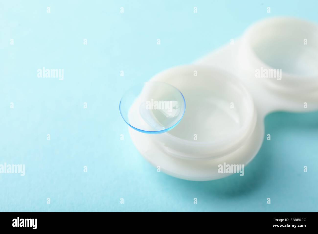 Lenti a contatto e custodia su sfondo turchese chiaro, primo piano. Spazio per il testo Foto Stock