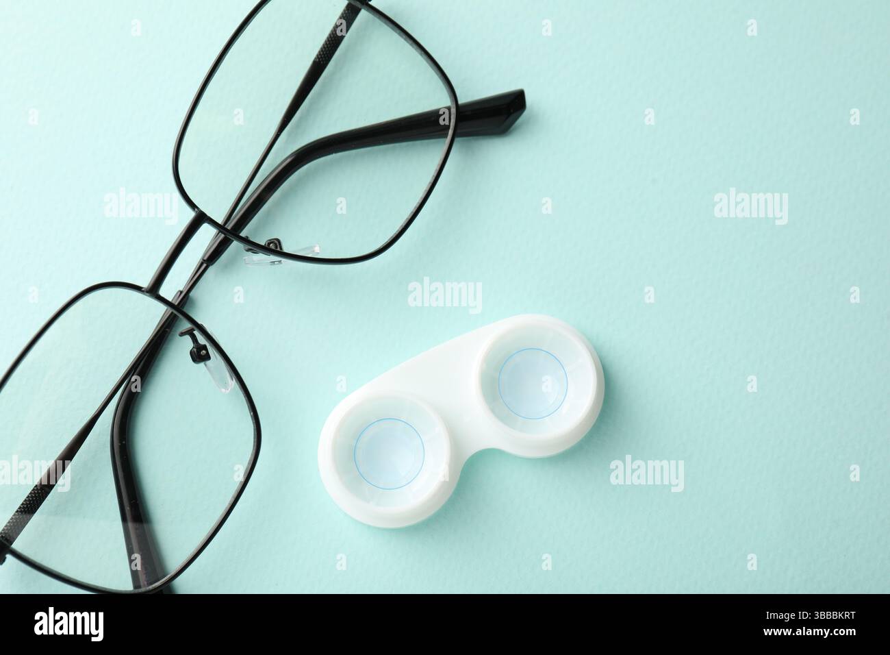 Lenti a contatto in astuccio e occhiali su sfondo turchese chiaro, piatto Foto Stock