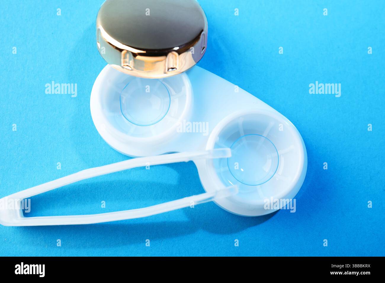 Lenti a contatto in astuccio e pinzette su sfondo blu, piatto Foto Stock