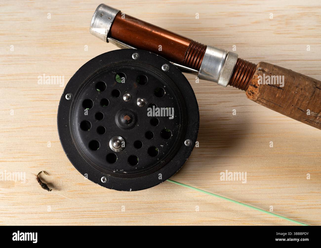 Vecchio flyrod e mulinello con una piccola ninfa su un tavolo. Foto Stock