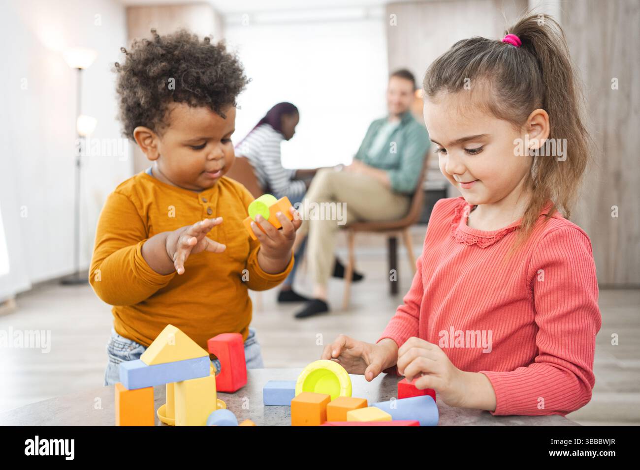Famiglia multirazziale che si diverte a giocare a casa con blocchi colorati Foto Stock