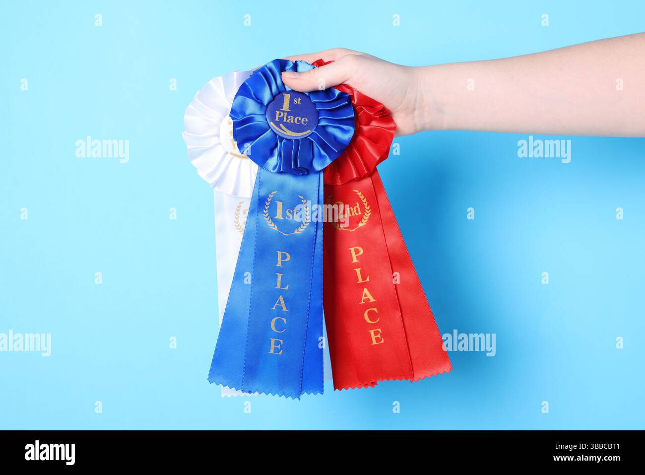 Donna che tiene nastri premio su sfondo azzurro, primo piano Foto Stock