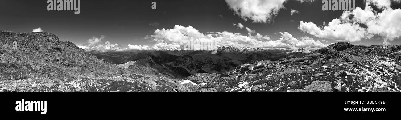 Una vista panoramica monocromatica di un paesaggio montuoso con spettacolari nuvole sopra, che enfatizza la maestosità della natura. Il terreno accidentato e il cielo creano Foto Stock