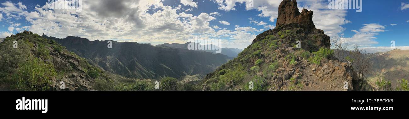 Una splendida immagine panoramica che mostra scogliere rocciose e lussureggianti valli verdi, con nuvole vibranti che aggiungono profondità alla scena. Perfetto per la natura, i viaggi, Foto Stock