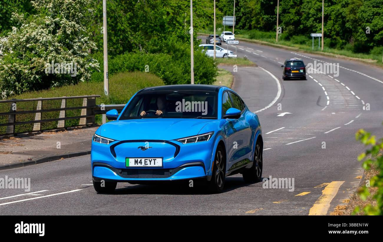 Milton Keynes, Regno Unito - 11 maggio 2025: 2021 auto elettrica Ford Mustang blu che guida su una strada britannica. Foto Stock